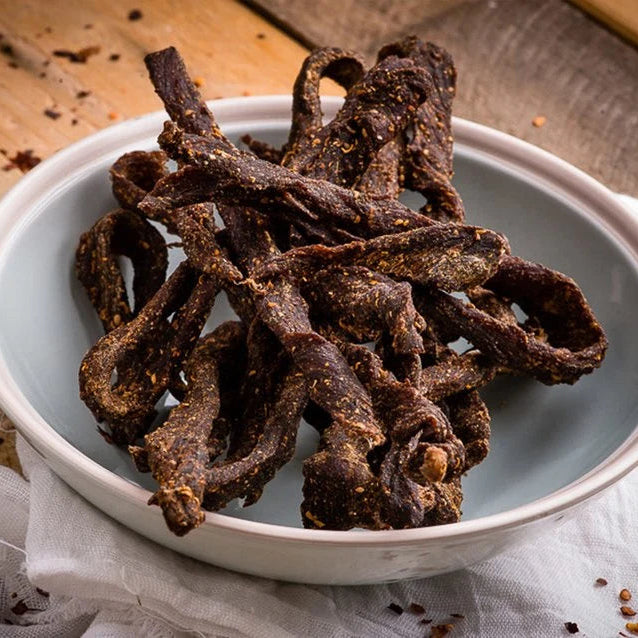 A bowl of Raw Sintra spicy beef chilli sticks on a wooden table
