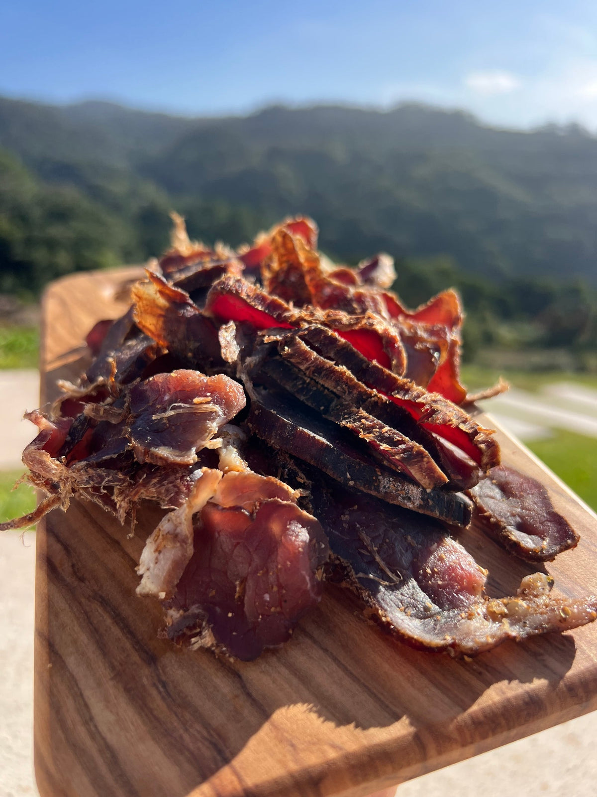 A bag of Raw Sintra Biltong in front of two trays of freshly sliced air-dried beef